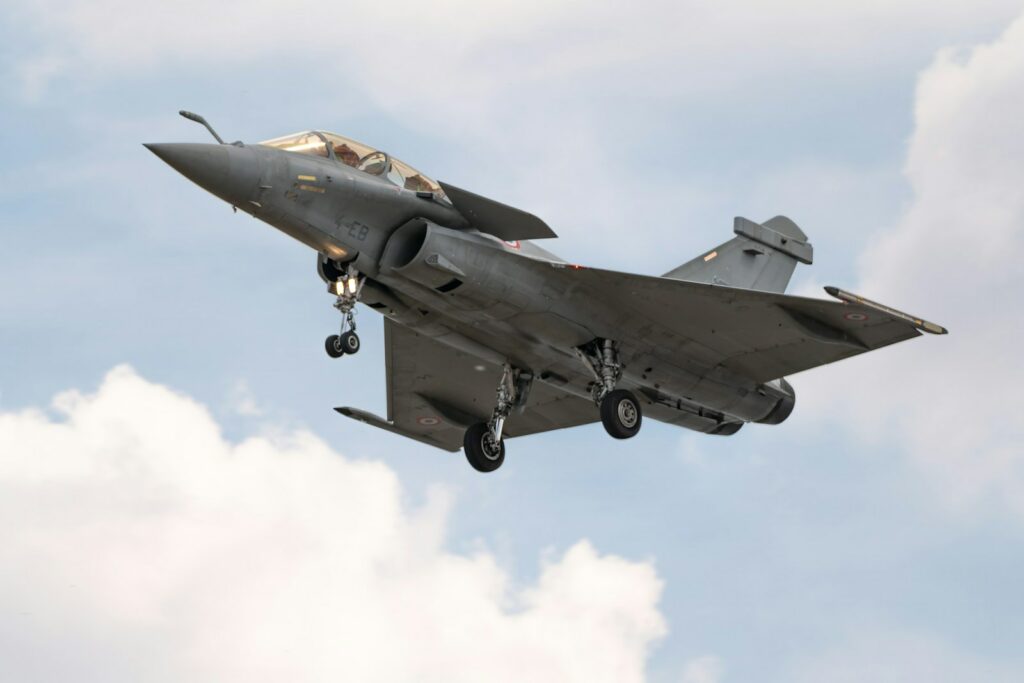 a fighter jet flying through a cloudy blue sky